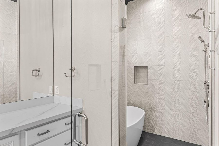 Stunning ensuite shower with floor-to-ceiling tile, frameless glass enclosure, and modern fixtures that create a spa-like experience.