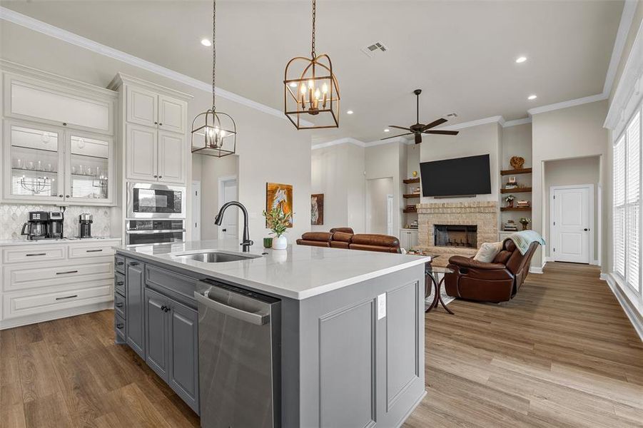 Kitchen open to the living area featuring quartz countertops, decorative pendant lighting, and walk-in pantry. Kitchen open to the living area featuring quartz countertops, decorative pendant lighting, and walk-in pantry.