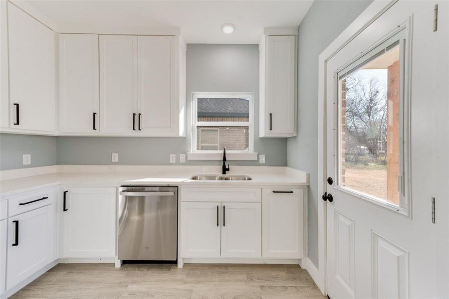 Kitchen featuring white cabinetry, light hardwood / wood-style floors, dishwasher, and sink