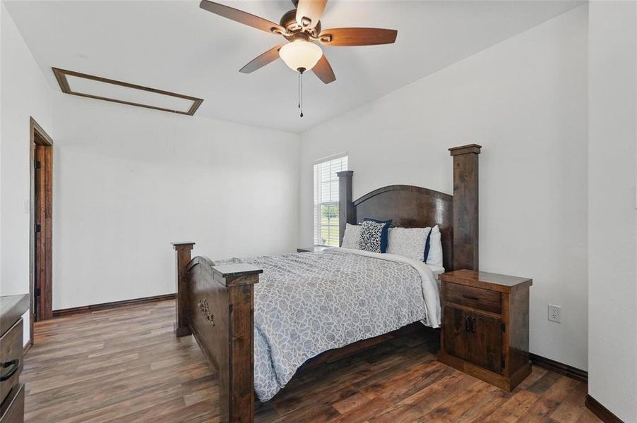 Bedroom featuring dark wood-style flooring, a ceiling fan, and attic access Bedroom featuring dark wood-style flooring, a ceiling fan, and attic access