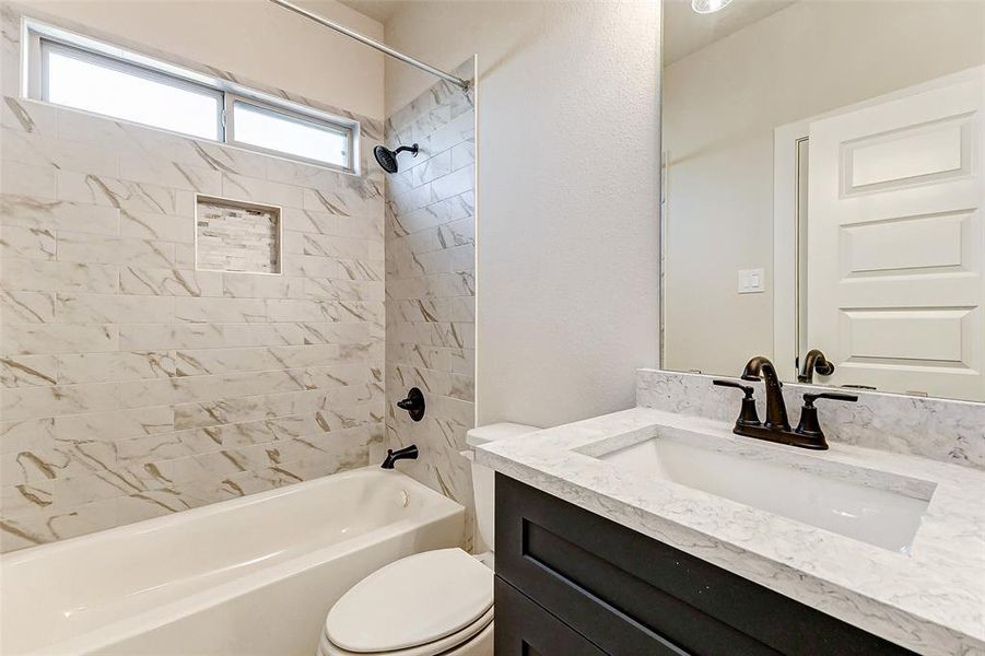 Indulge in the elegance of this spa-inspired bathroom. A stunning tiled shower with intricate accents complements the sleek vanity with quartz countertops and modern fixtures. Natural light pours through the high window, adding a serene ambiance.