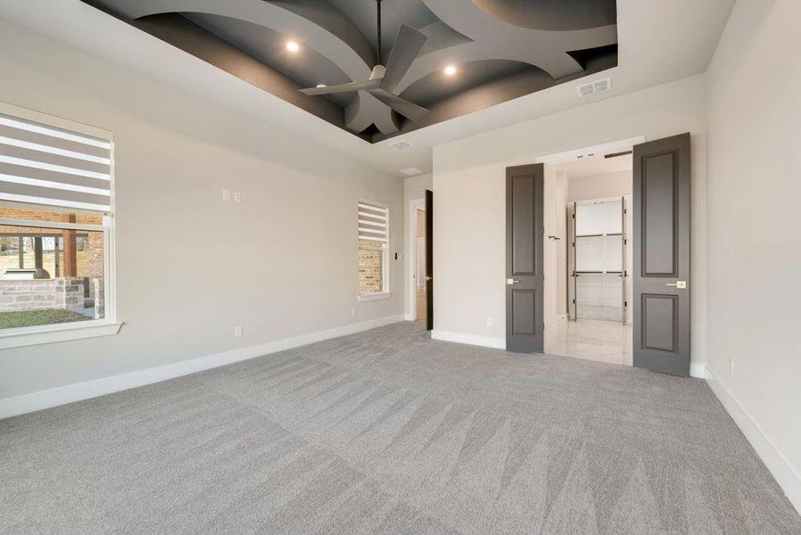 Unfurnished bedroom featuring a high ceiling, ceiling fan, and light colored carpet