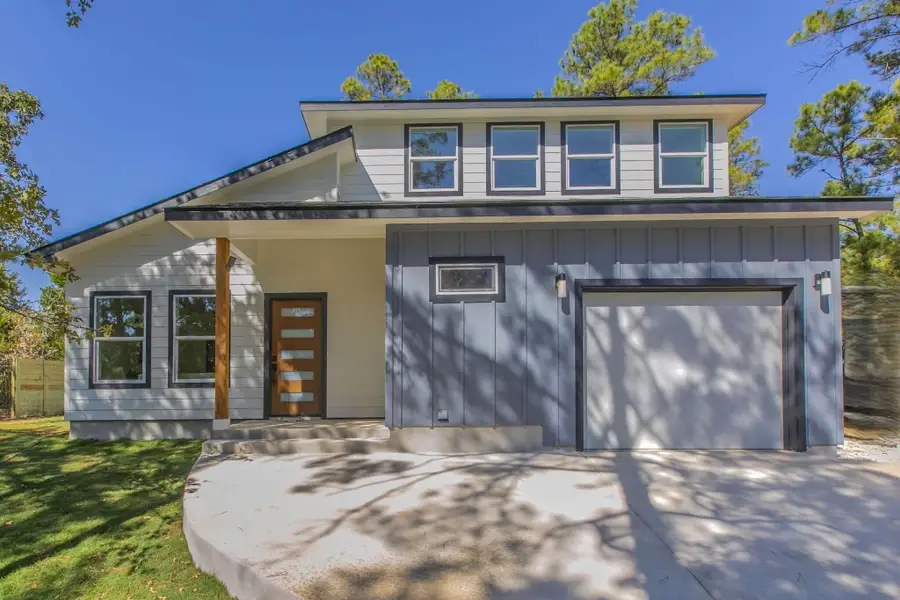 View of front of house with board and batten siding, driveway, an attached garage, and a front yard