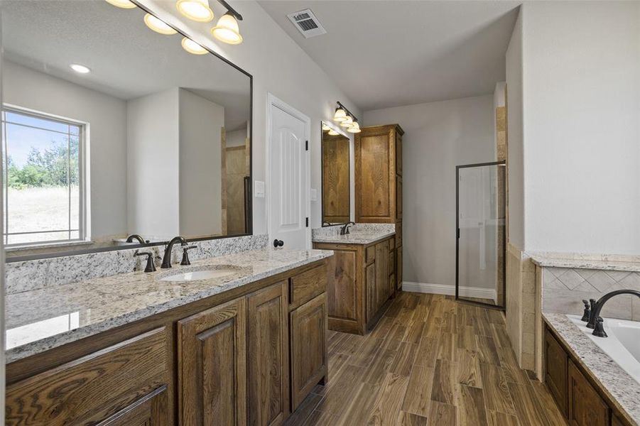 Bathroom featuring double vanity, wood-type flooring, and independent shower and bath