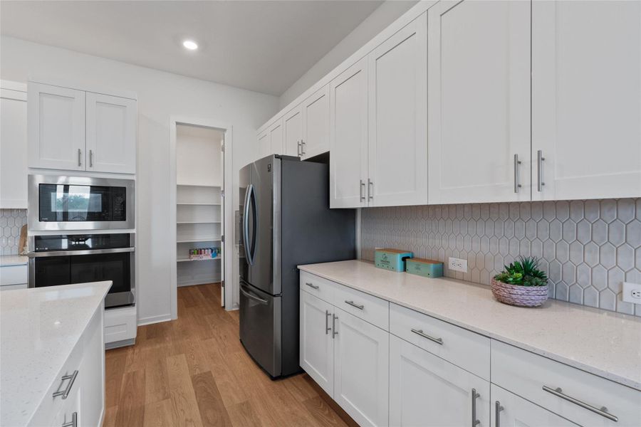 A contemporary kitchen features bright white cabinetry and an inviting walk-in pantry.