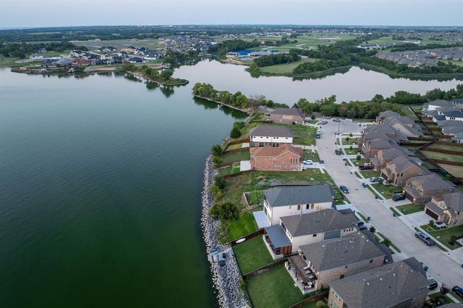 Aerial view of property and surrounding area featuring a nearby body of water and nearby suburban area