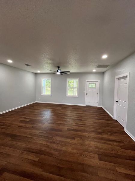 Unfurnished living room with plenty of natural light, a textured ceiling, dark wood-type flooring, recessed lighting, and a ceiling fan Unfurnished living room with plenty of natural light, a textured ceiling, dark wood-type flooring, recessed lighting, and a ceiling fan