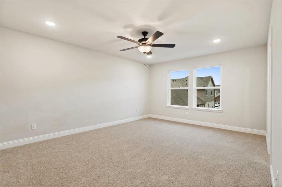 Carpeted empty room featuring ceiling fan