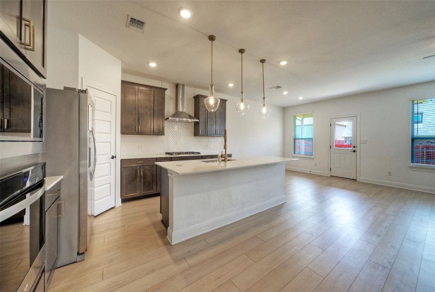 Plank flooring runs through an open layout connecting the kitchen to the living space. Plank flooring runs through an open layout connecting the kitchen to the living space.