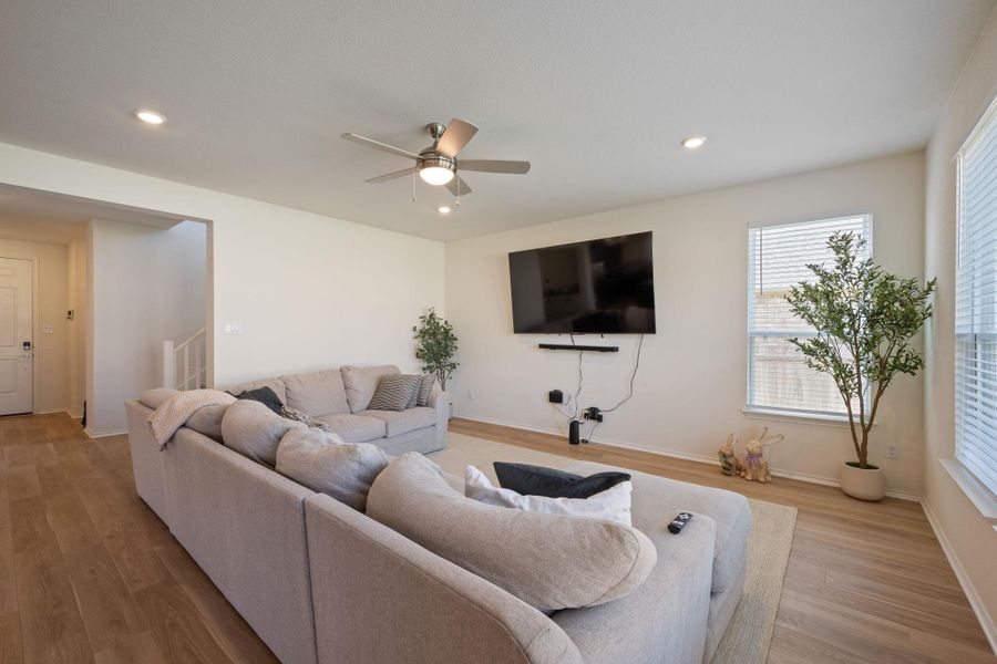 Living room with light wood-style flooring, a ceiling fan, and recessed lighting