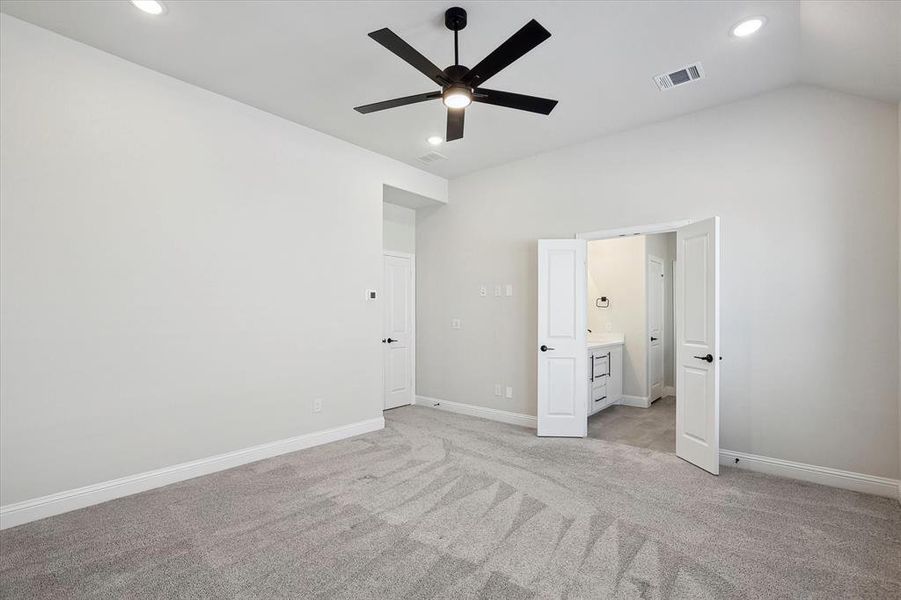 Unfurnished bedroom featuring light colored carpet, lofted ceiling, recessed lighting, baseboards, and connected bathroom