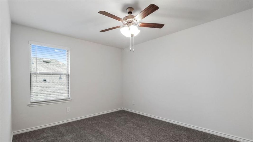 Spare room featuring dark carpet and ceiling fan Spare room featuring dark carpet and ceiling fan