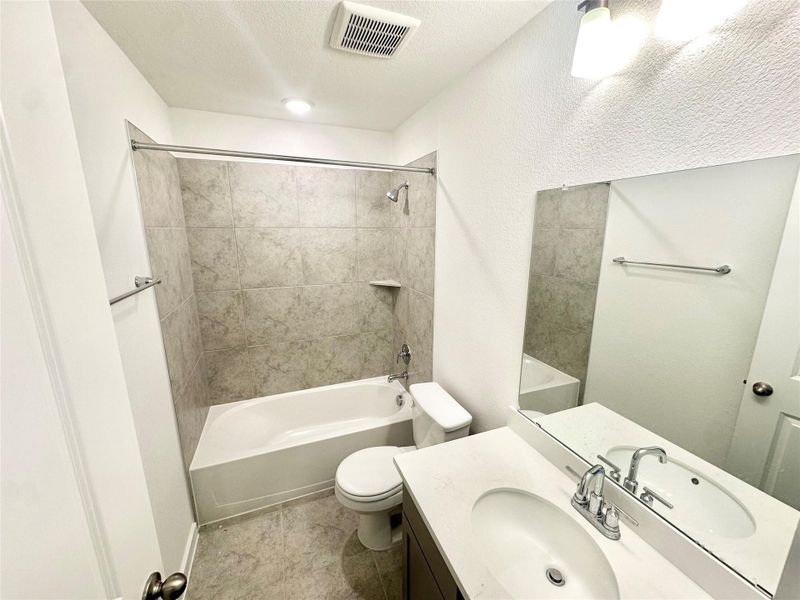 Bathroom with tub / shower combination, vanity, and a textured ceiling