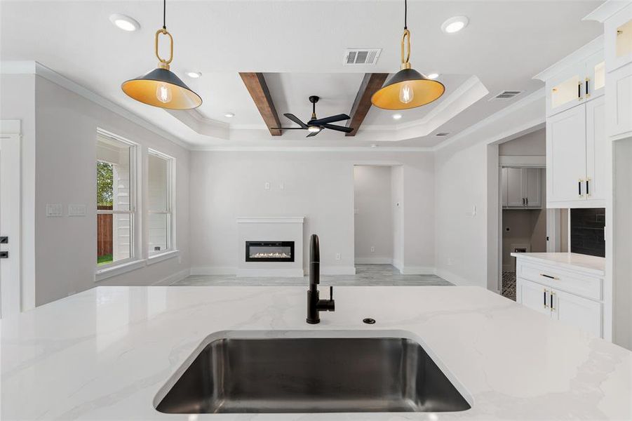 Kitchen featuring a raised ceiling, sink, ceiling fan, and pendant lighting