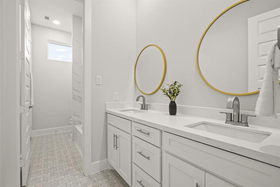 Both Secondary Bedrooms have access to this Full Bath. The space boasts quartz countertops, two undermount sinks, brushed nickel hardware, soft-close cabinets, and framed mirrors. To the left, not pictured, is a closet that can hold extra linens, towels, and toiletries.