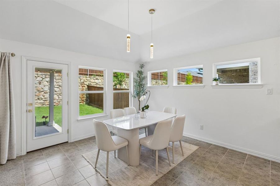 Dining area featuring a white vaulted ceiling and tile flooring
