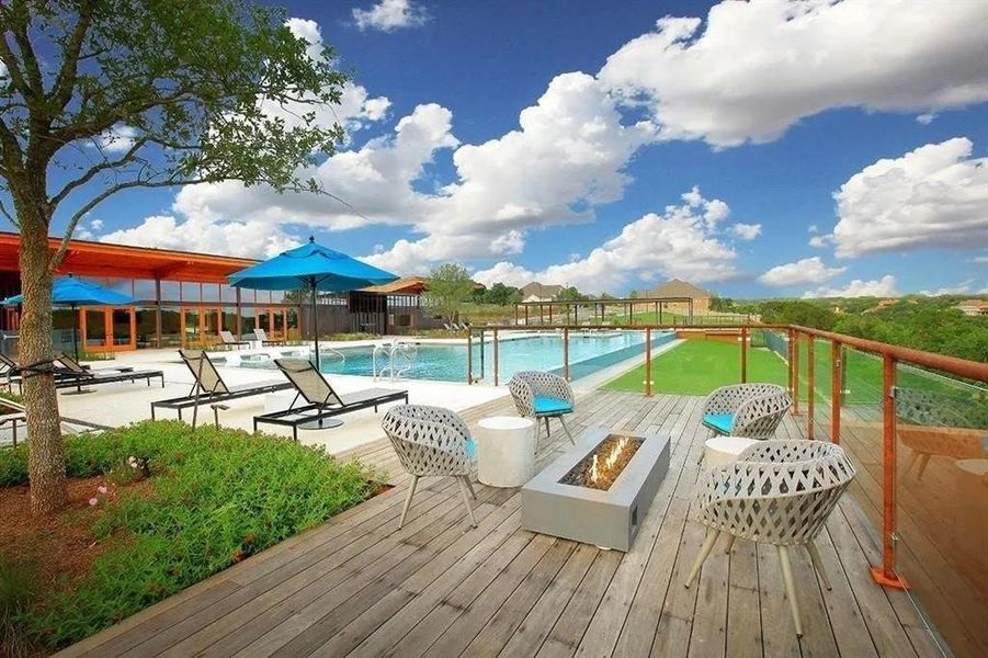 An inviting outdoor deck features a fire pit, overlooking a pristine pool and distant landscape.
