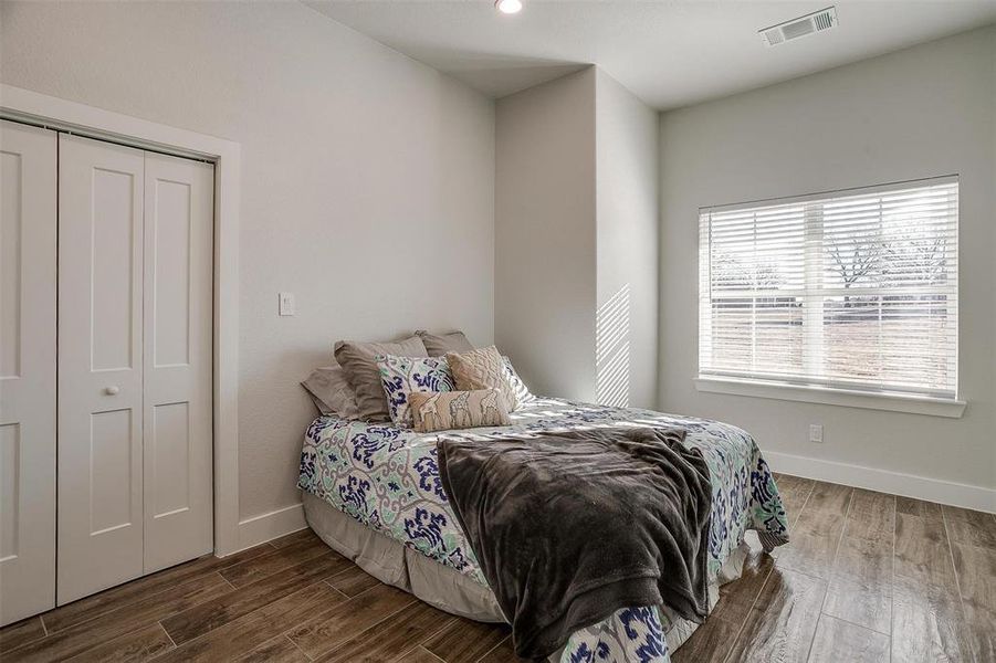 Bedroom with dark wood-type flooring and a closet