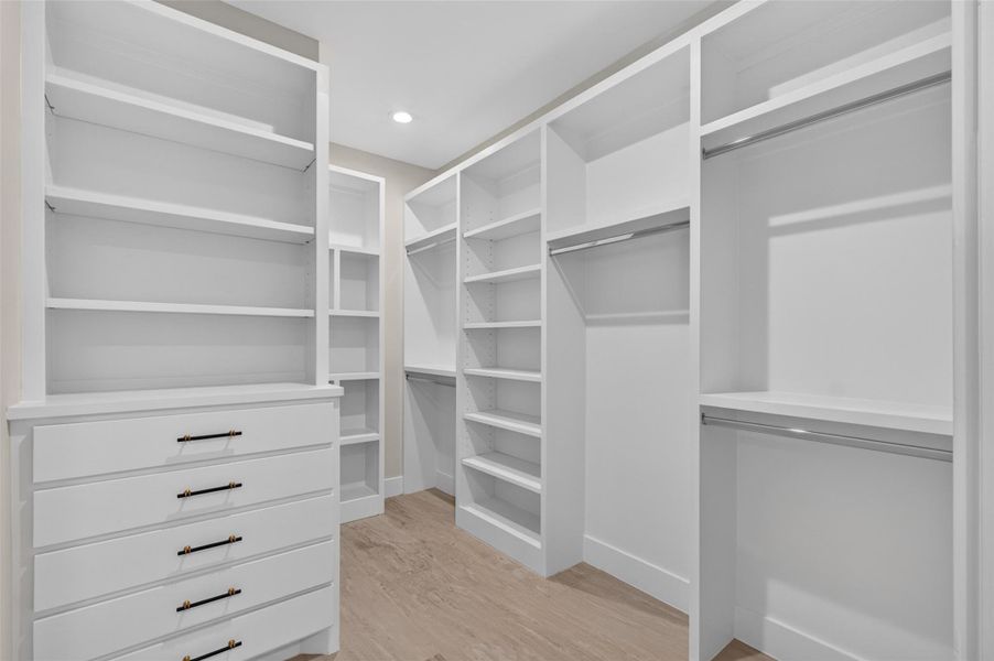 Spacious walk-in closet with ample shelving and hanging space, complemented by elegant drawers and sleek hardware, perfect for organized storage.