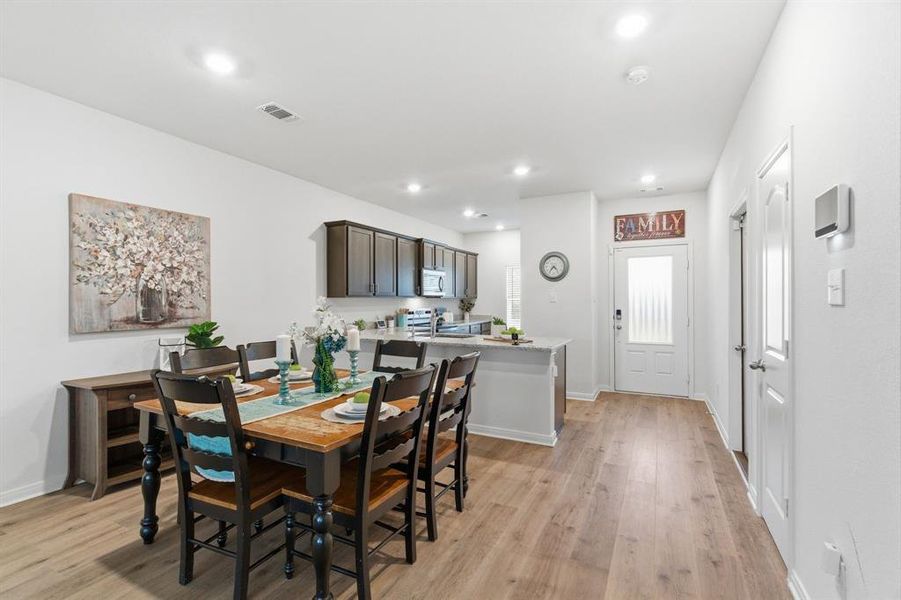Open concept living area featuring hardwood style flooring, recessed lighting, and a kitchen with dark wood cabinetry and a light-colored countertop