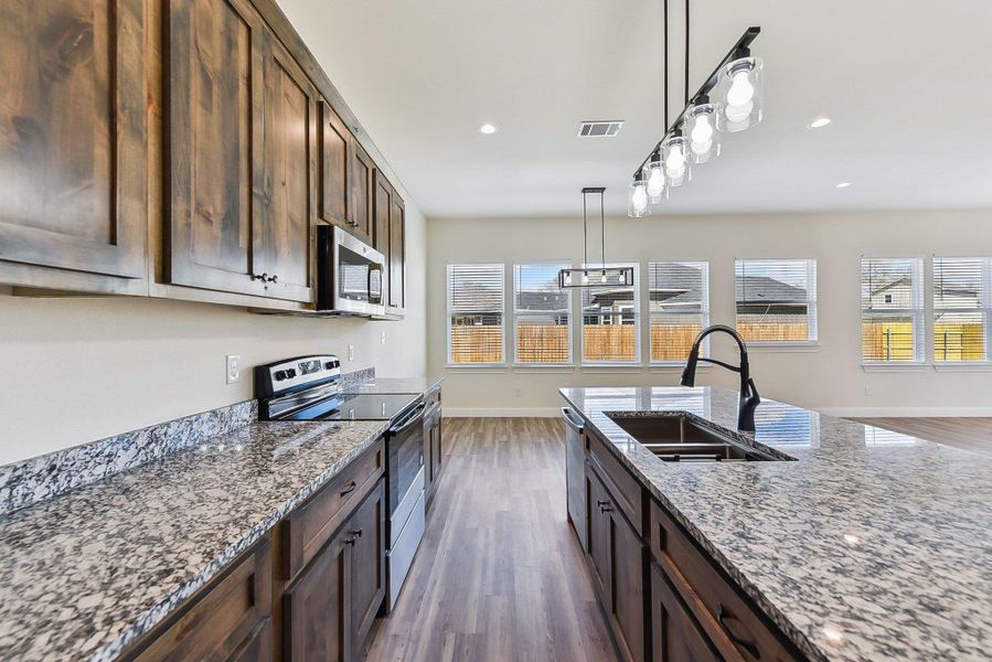 Kitchen with a wealth of natural light, appliances with stainless steel finishes, light stone countertops, and a sink Kitchen with a wealth of natural light, appliances with stainless steel finishes, light stone countertops, and a sink