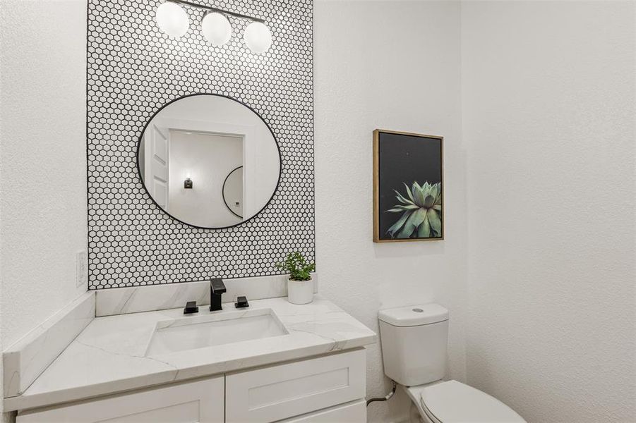 Half bath featuring vanity and a textured wall
