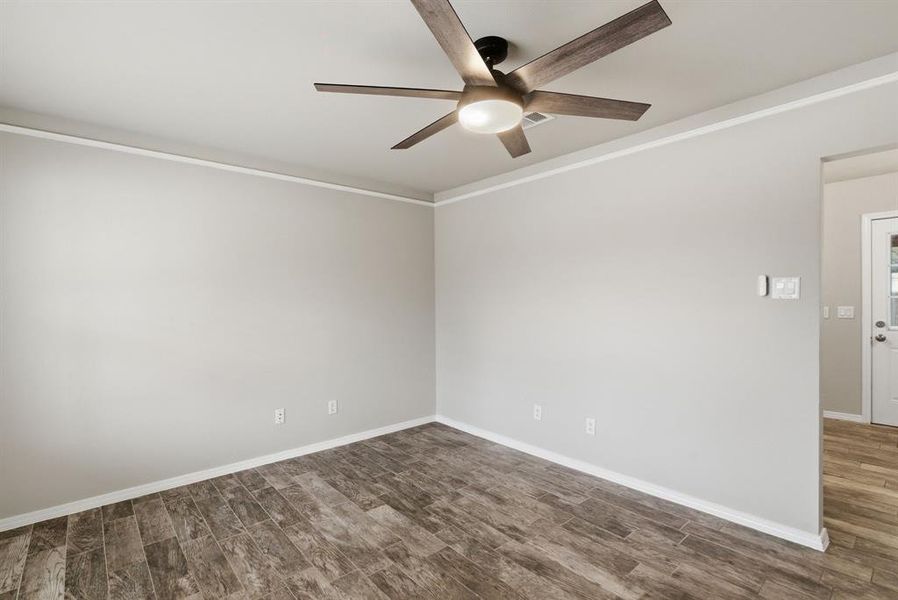 Spare room with ornamental molding, dark wood-style floors, and ceiling fan Spare room with ornamental molding, dark wood-style floors, and ceiling fan