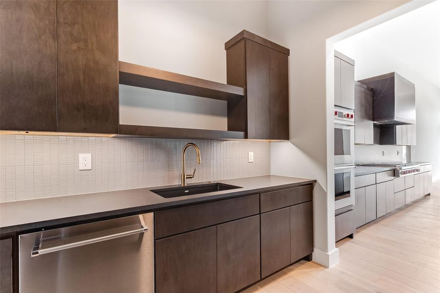 Kitchen featuring appliances with stainless steel finishes, a sink, open shelves, and dark brown cabinets Kitchen featuring appliances with stainless steel finishes, a sink, open shelves, and dark brown cabinets