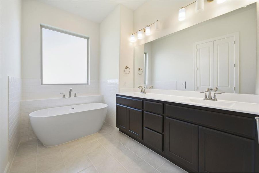 Freestanding soaking tub with brushed nickel fixtures, complemented by a dual vanity featuring dark wood cabinetry and white countertops
