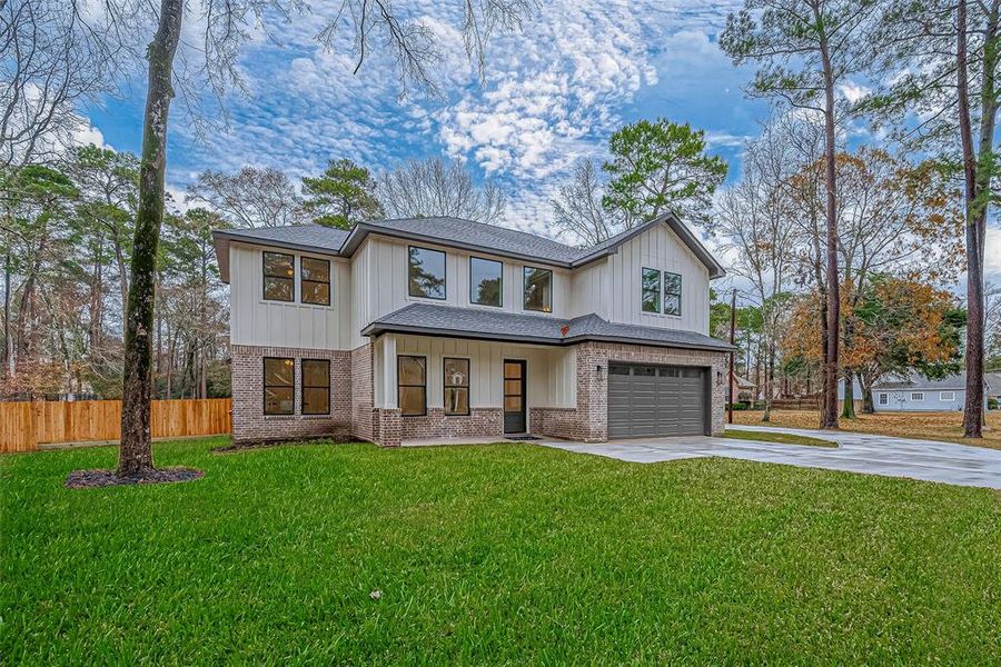 Two-story home with a brick and siding exterior,  surrounded by mature trees and a wooden fence.