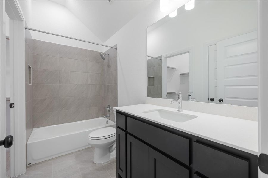 Full bathroom with vanity, bathtub / shower combination, vaulted ceiling, and light tile patterned floors