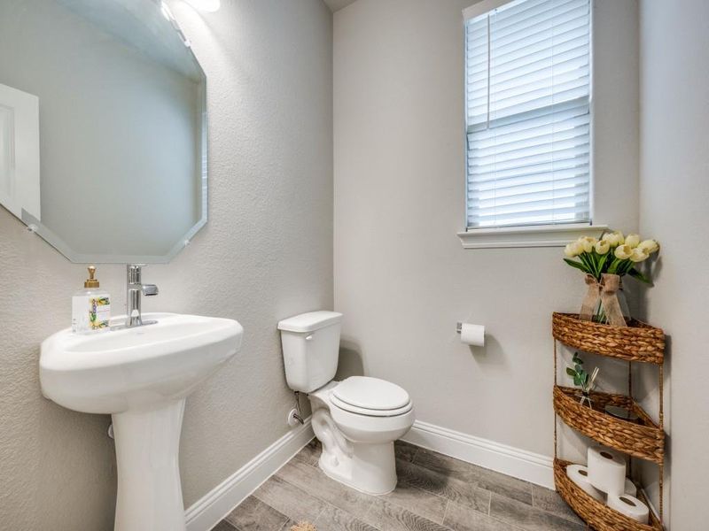 Well-appointed half bath features a classic pedestal sink and tasteful finishes.