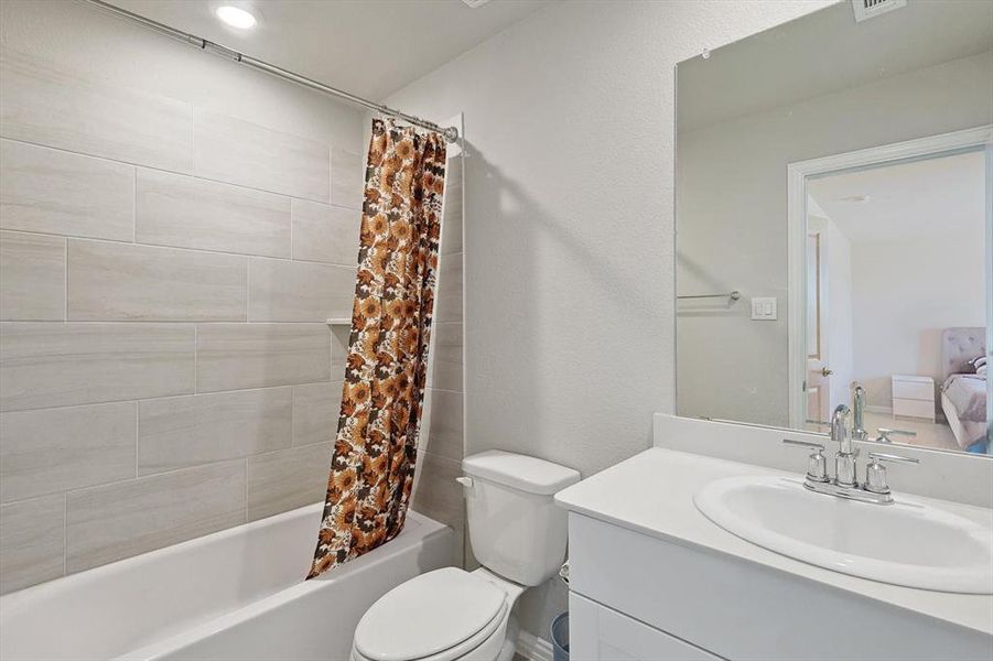 Full bathroom featuring shower / bathtub combination with curtain, oversized vanity, and toilet