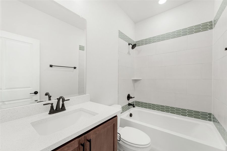 Bathroom with white quartz vanity, soaking tub, and tiled shower surround with green hexagon accent tiles Bathroom with white quartz vanity, soaking tub, and tiled shower surround with green hexagon accent tiles