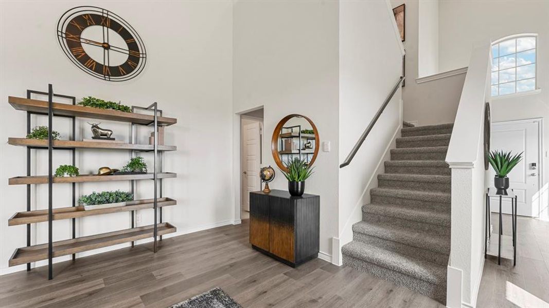 Staircase featuring a towering ceiling and wood finished floors Staircase featuring a towering ceiling and wood finished floors