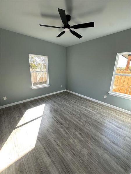 Unfurnished room featuring dark wood-type flooring and ceiling fan