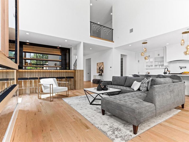 Living room with a towering ceiling, light wood-type flooring, and sink