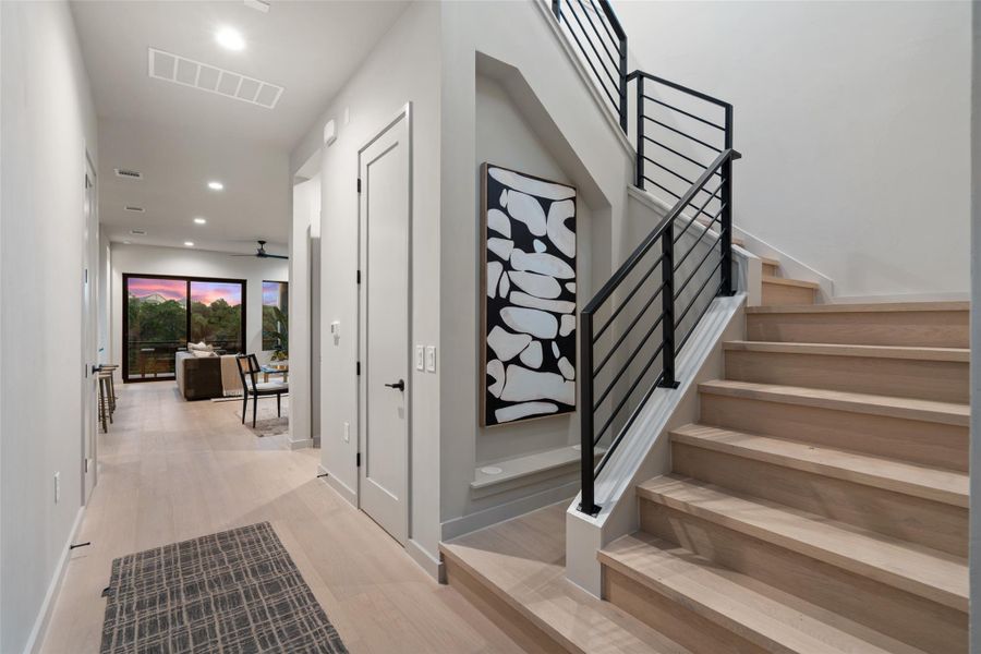 An inviting entry hallway with light hardwood flooring leads to a contemporary staircase with sleek metal railings. An inviting entry hallway with light hardwood flooring leads to a contemporary staircase with sleek metal railings.