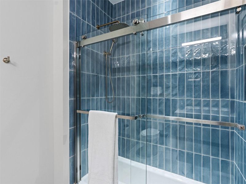 Shower enclosure featuring clear glass sliding doors and brushed metal hardware Shower enclosure featuring clear glass sliding doors and brushed metal hardware