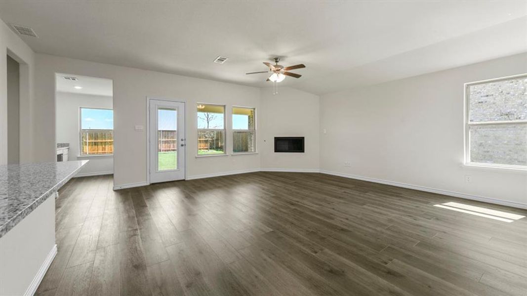 Expansive living area featuring wood-look flooring, a ceiling fan, and large windows providing natural light