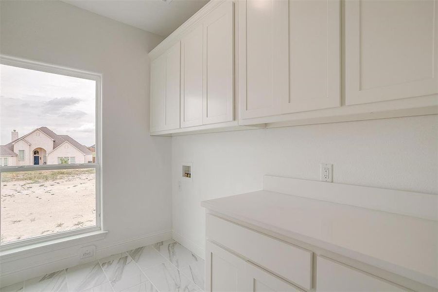 Clothes washing area featuring washer hookup and cabinets