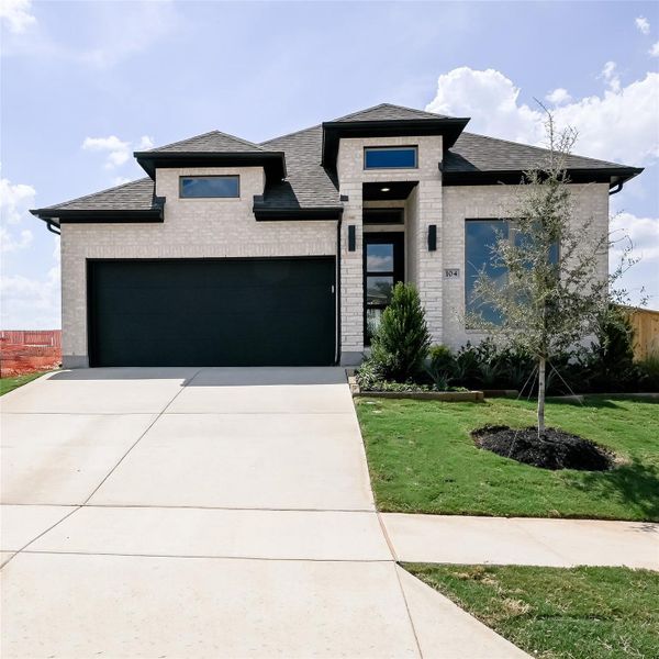View of front of home with brick siding, a shingled roof, concrete driveway, and a front yard View of front of home with brick siding, a shingled roof, concrete driveway, and a front yard