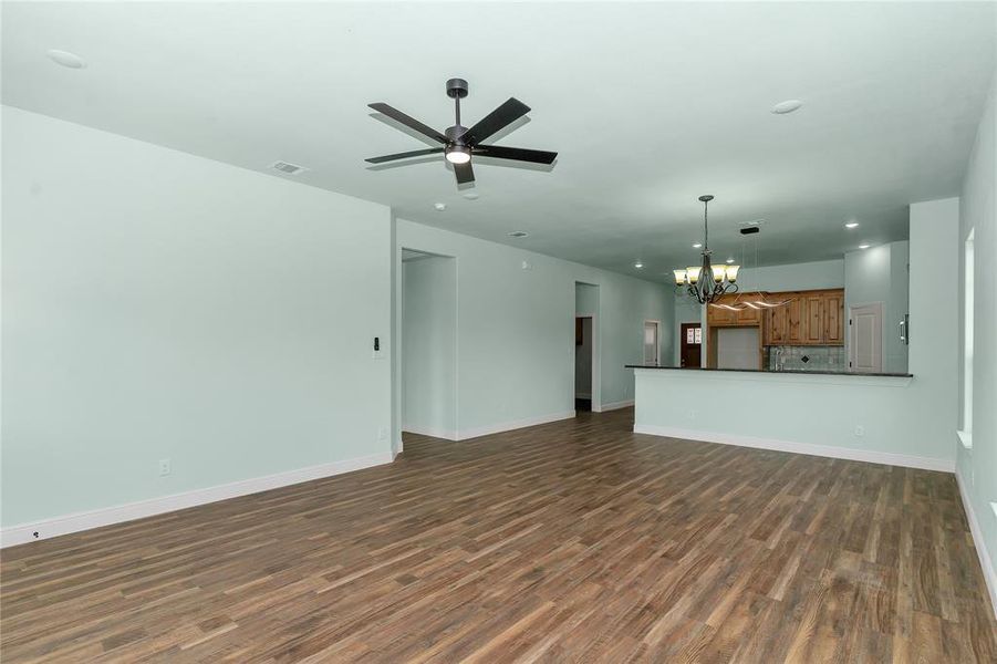 Unfurnished living room featuring a chandelier, dark wood finished floors, recessed lighting, and ceiling fan