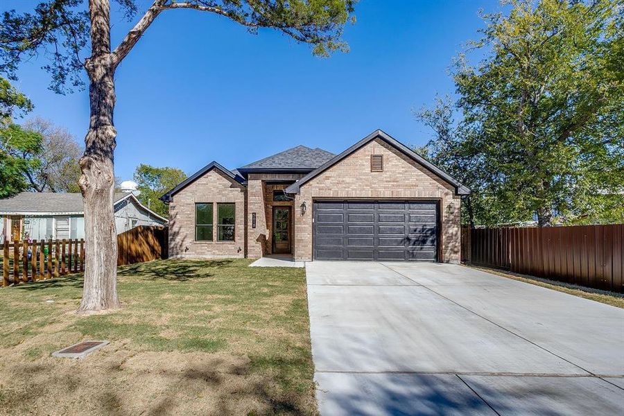 View of front of property featuring driveway, brick siding, roof with shingles, and an attached garage