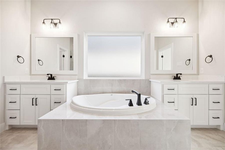 Bathroom featuring vanity and tiled bath