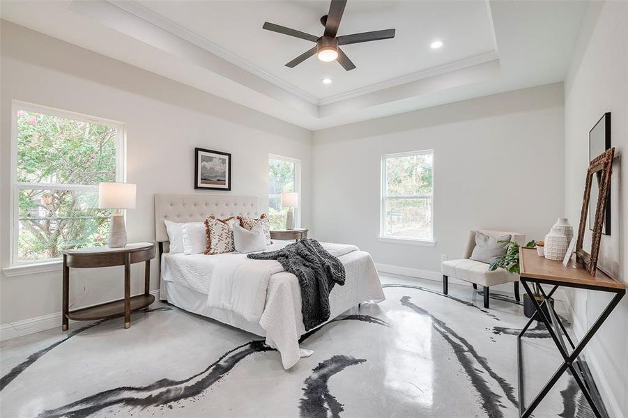 Primary Bedroom featuring ceiling fan, crown molding, and a tray ceiling