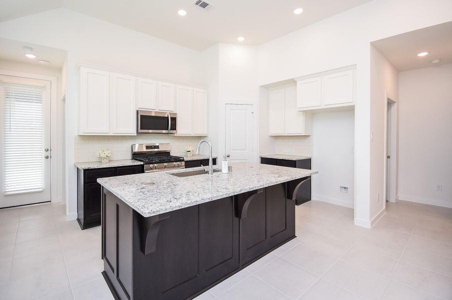 Classic white cabinetry and kitchen walls offer an instant sense of warmth in this space. Dark chocolate colored cabinetry is complemented by light granite counter tops and tile backsplash, wherever your tasks take you. Refrigerator in included.