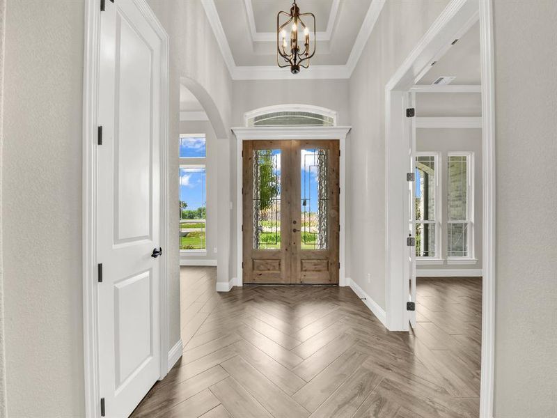Entryway with a chandelier, arched walkways, baseboards, crown molding, and french doors Entryway with a chandelier, arched walkways, baseboards, crown molding, and french doors