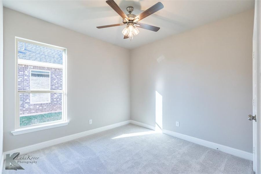 Carpeted empty room featuring baseboards and a ceiling fan