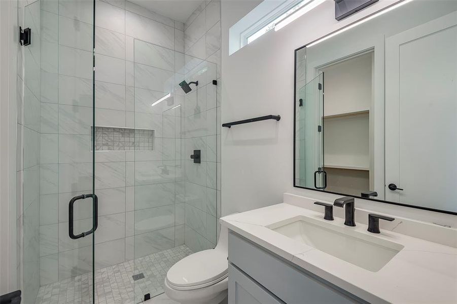 Guest Bathroom with an enclosed shower, vanity, and toilet